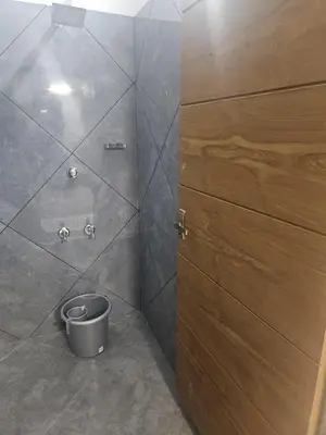 a bathroom with a shower with a bucket next to a door at Regent Tourist Home in Palakkad
