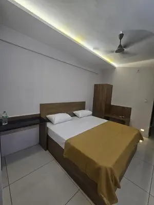 a bedroom with a bed with a yellow blanket on it at Regent Tourist Home in Palakkad