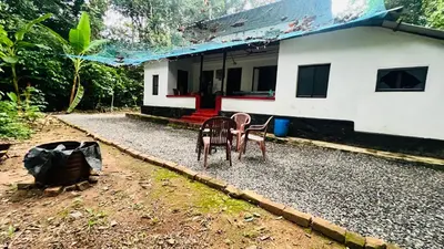 a house with two chairs sitting in front of it at Tharavadu Homestay in Athirappilly