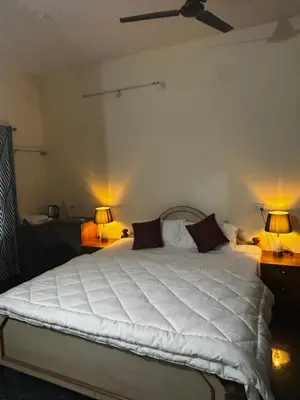 a bedroom with a large white bed with two lamps at Kings Villa Mysore in Mysore