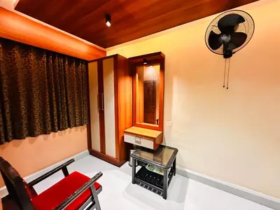 a room with a red chair and a mirror at City Palace Hotel in Ooty