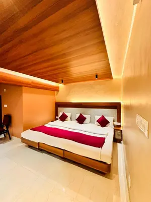 a bedroom with a large bed with red pillows at City Palace Hotel in Ooty