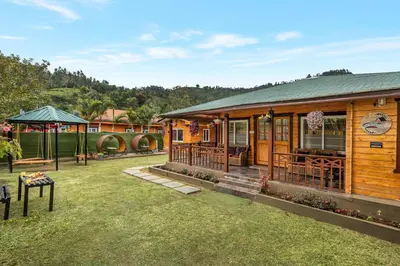 a wooden cabin with a grass yard in front of it at StayVista at The Woodscapes with Lawn & Views in Ooty