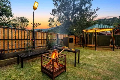 a fire pit in a yard next to a fence at StayVista at The Woodscapes with Lawn & Views in Ooty