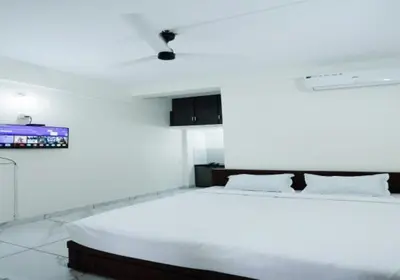 a white bedroom with a large bed and a tv at Hotel Diamond Castle in Manjeri