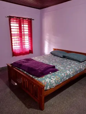 a bed in a bedroom with a red window at Keerthis Home Stay in Madikeri
