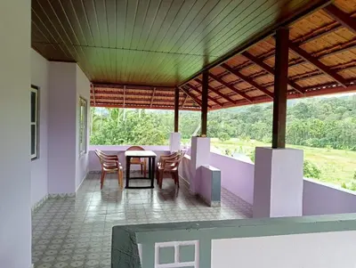 a dining room with a table and chairs on a balcony at Keerthis Home Stay in Madikeri