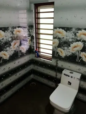 a bathroom with a toilet and flowers on the wall at Keerthis Home Stay in Madikeri
