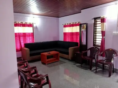 a living room with a black couch and chairs at Keerthis Home Stay in Madikeri