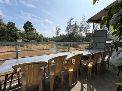 a wooden table and chairs on a deck at Glasshouse Retreat by The Jungle stay groups in Vālpārai