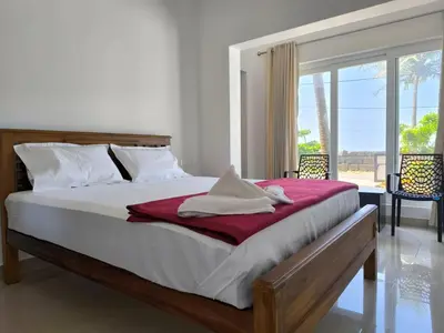 a bedroom with a large bed with a red blanket at Sea Breeze Cherai Homestay in Pallipuram