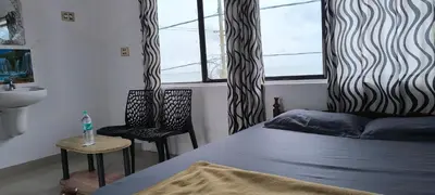 a bedroom with a bed and two chairs and a window at Sea Breeze Cherai Homestay in Pallipuram