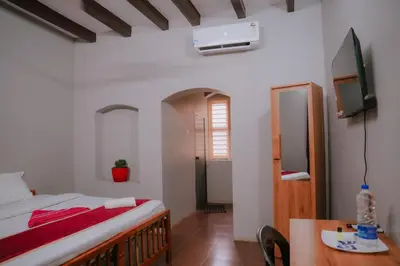 a bedroom with a bed and a table and a tv at ERA Heritage Inn in Kozhikode