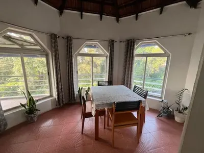 a dining room with a table and two windows at Fireflies R in Madikeri