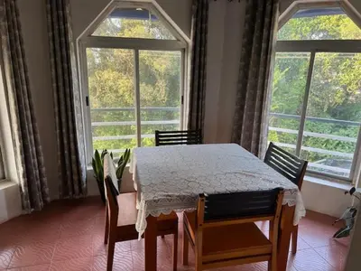 a dining room with a table and chairs and windows at Fireflies R in Madikeri