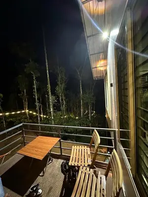 a table and chairs on a balcony at night at Pepper Mist Wayanad Homestay in Tindummal