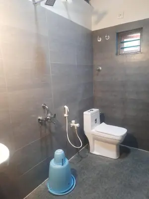 a bathroom with a toilet and a shower stall at Spinson Home Stay in Madikeri