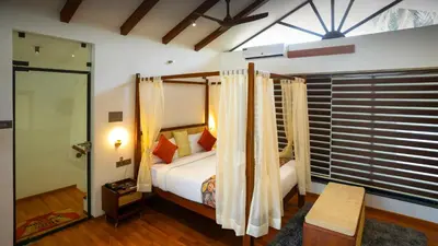 a bedroom with a bed with curtains and a window at Sakthi River Resort in Pollāchi