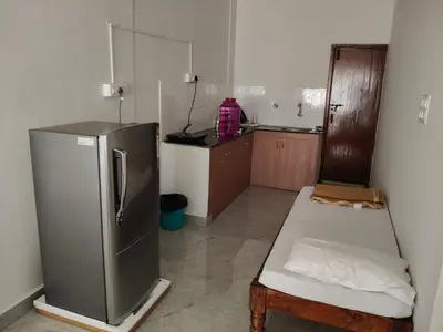 a small kitchen with a refrigerator and a table at Temple Bells in Mysore