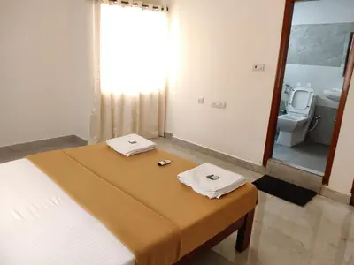 a bedroom with a bed and a bathroom with a toilet at Temple Bells in Mysore