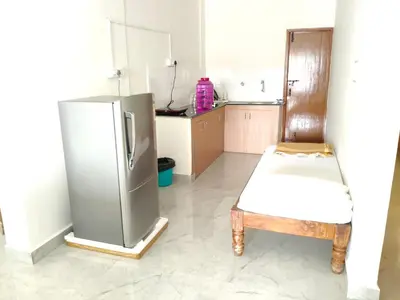 a kitchen with a stainless steel refrigerator and a chair at Temple Bells in Mysore