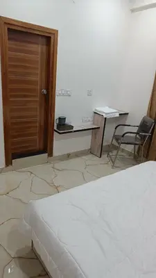 a bedroom with a bed and a desk and a chair at Eve Service apartment in Mysore