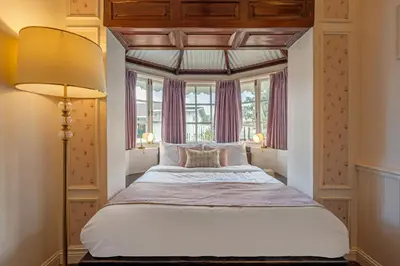 a bedroom with a large bed with a large window at Tiverton Bungalow in Ooty