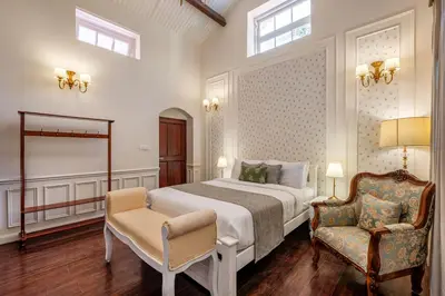 a bedroom with a large bed and a chair at Tiverton Bungalow in Ooty