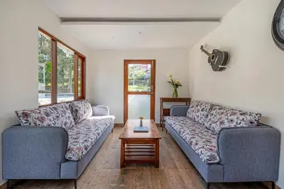 a living room with two couches and a table at Tiverton Bungalow in Ooty