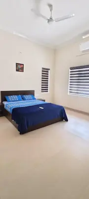 a bedroom with a blue bed in a white room at Aura Villa in Kozhikode