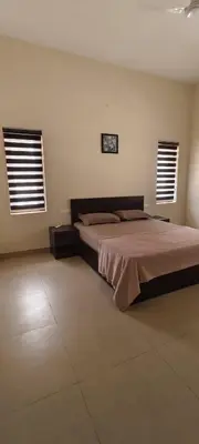 a bedroom with a large bed and two windows at Aura Villa in Kozhikode