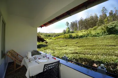 a balcony with a table and a view of a field at Green Leaves The Countryside Inn in Ooty