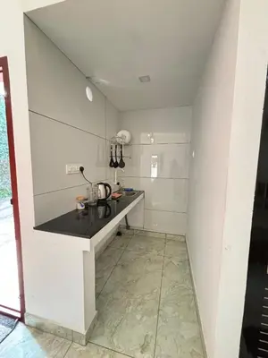 a kitchen with a counter in the middle of a room at GRAYSTONE HOMESTAY, Omassery in Tāzhekkod