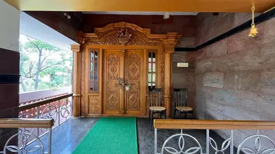 a room with a wooden door with a bench and chairs at Vasantham Home Stay in Satyamangalam