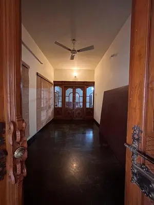 an empty room with a ceiling fan and wooden doors at Vasantham Home Stay in Satyamangalam