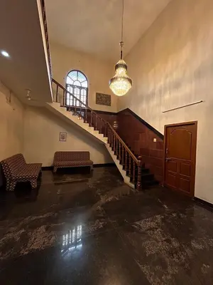 an empty room with a staircase and a chandelier at Vasantham Home Stay in Satyamangalam