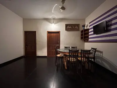 a dining room with a table and chairs and a television at Vasantham Home Stay in Satyamangalam