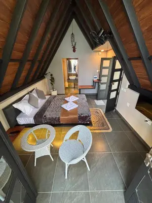 a bedroom with a bed and a table and chairs at Cicadas Nature Resort - A Frame cottages in Wayanad