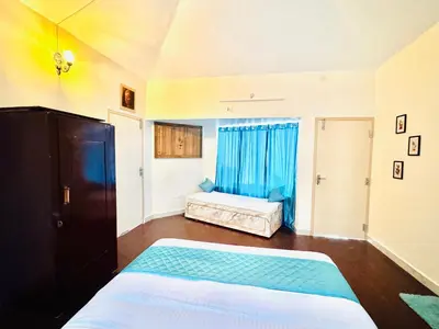 a bedroom with a bed and blue curtains at BR Villa in Kodaikānāl