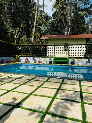 a swimming pool with a house in the background at Wild mist in Padinjarathara