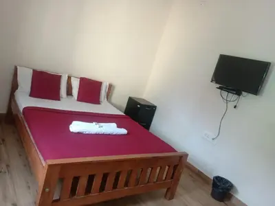 a small bedroom with a bed with red sheets and a tv at MM comforts in Mysore