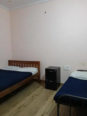 a room with two beds and a table in it at MM comforts in Mysore