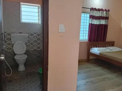 a bathroom with a toilet and a bed and a window at MM comforts in Mysore