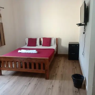 a bedroom with a wooden bed with red sheets at MM comforts in Mysore