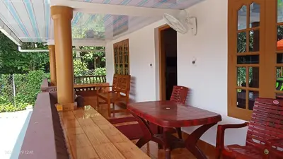 a porch with a wooden table and chairs on a house at Diamond Villas Wayanad Entire Villa booking in Mananthavady