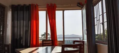 a dining room with a table and chairs and windows at Dam Valley Home Stay Resort in Parambikolam