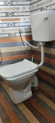 a bathroom with a white toilet in a room at Dam Valley Home Stay Resort in Parambikolam