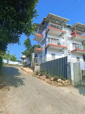 a building with a fence in front of it at Dam Valley Home Stay Resort in Parambikolam