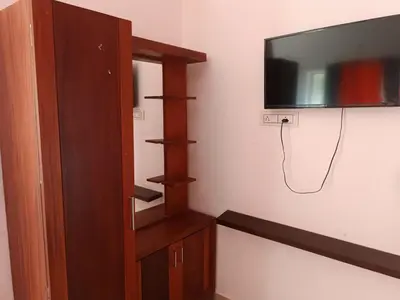 a living room with a tv on a wall at Dam Valley Home Stay Resort in Parambikolam