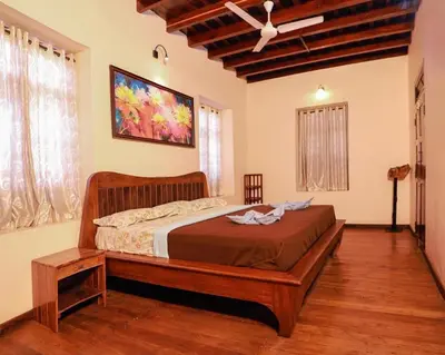 a bedroom with a bed and a ceiling fan at Dhanagiri Homestay Wayanad in Vythiri